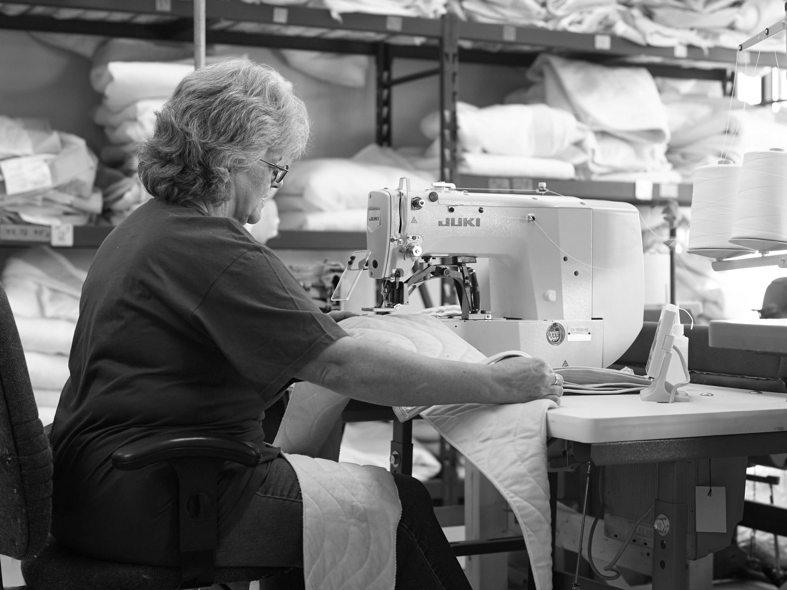 Person operating a sewing machine in a warehouse setting